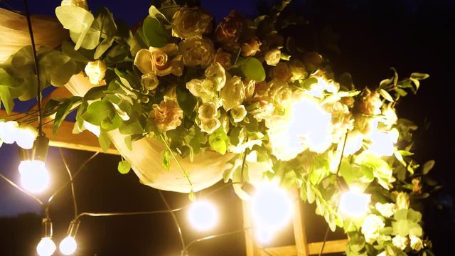 Closeup view of top of beautiful floral night wedding decorations with soft light of lamps. Real time 4K video footage.