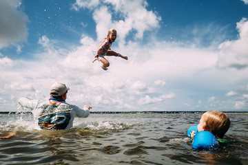 Man throwing girl in air in ocean