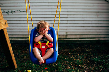 Child on swing with hands over eyes