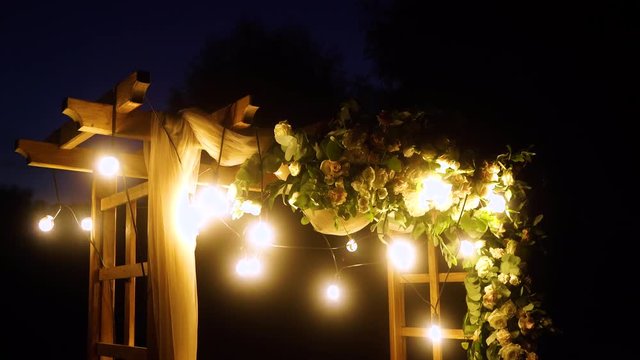 Beautiful place made with wooden square and floral decorations for outside wedding ceremony in night wood. Real time 4K video footage.