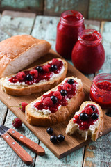 Tasty summer breakfast. Homemade berry jam on ciabatta toasts on old shabby blue boards