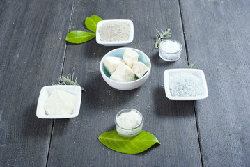 cosmetic clay powder, creams, shea butter and bath salt on old black wood table background