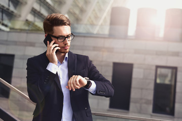 Serious business man talk on the phone in office park.