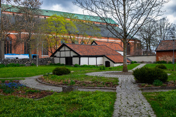 Fototapeta na wymiar Old brick buildings and a small park near the cathedral in the center of Swedish town Vasteras shot on a cloudy and rainy spring day