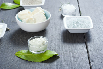 cosmetic clay powder, creams, shea butter and bath salt on old black wood table background