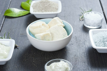 cosmetic clay powder, creams, shea butter and bath salt on old black wood table background