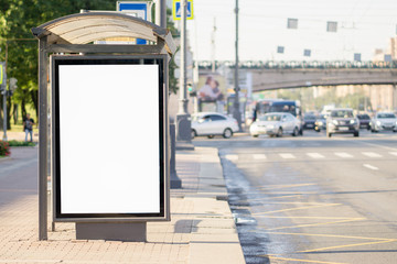 Blank white mock up of vertical light box in a bus stop in the afternoon on a city background