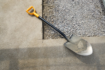 The shovel lies on the asphalt cut. with stones under it, a geometric composition.
