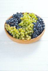 white and red grapes on wooden bowl, white wood table background