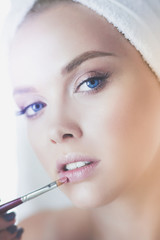 Young beautiful woman making make-up near mirror, in bathroom