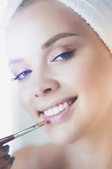 Young beautiful woman making make-up near mirror, in bathroom