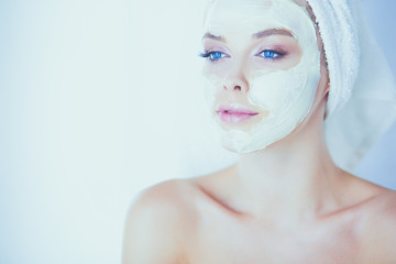 happy woman with a towel on her head puts on face mask