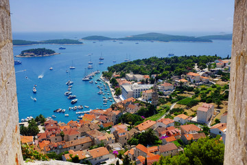 Hvar town harbor from the Spanish Fortress framed by a stone window