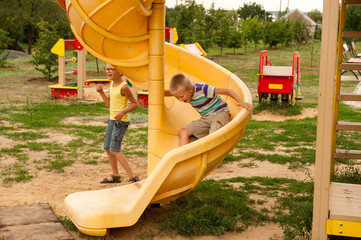 Happy village children came to city to play in playground. Funny child is riding toy car with...