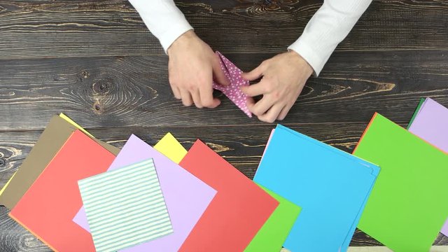 Making origami crane. Top view, hands making origami.