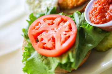 A hot, fresh, crab cake sandwich with tomato slices and sweet potato fries