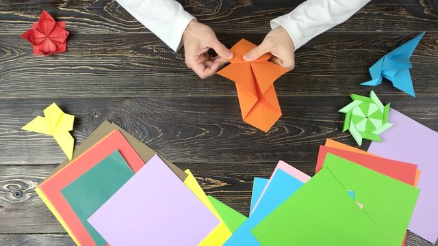 Male hands folding origami toy. Paper folding art. Top view.