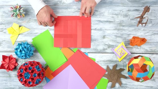 Folding red origami paper. Top view, origami figures on wooden table.