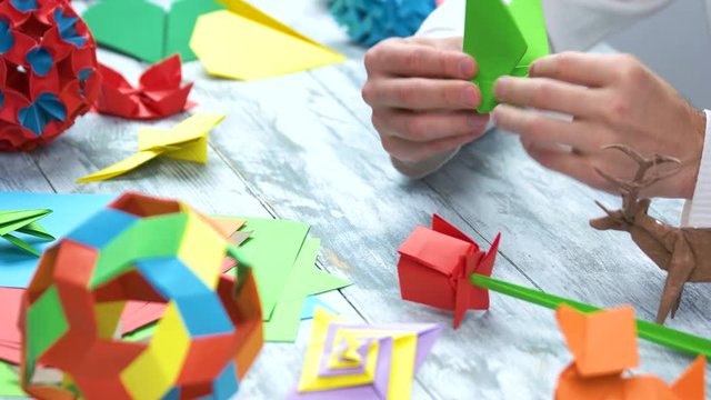 Making green origami paper crane close up. Male hands. Amazing hobby.