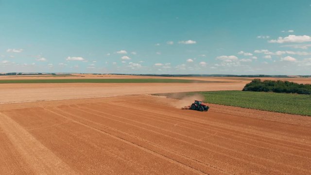 Aerial drone view of red tracor working in wheat field. Agriculture and environment in European Union.