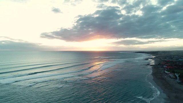 Sunset on the black sand beach, Indonesia, Bali. Aerial view. 4K