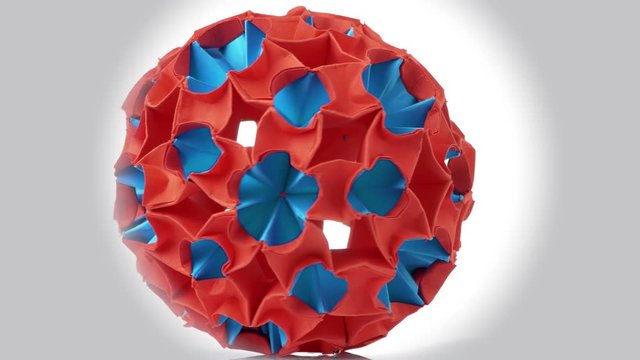 Origami Magic Ball. Amazing rotating red origami figure. White isolated background.