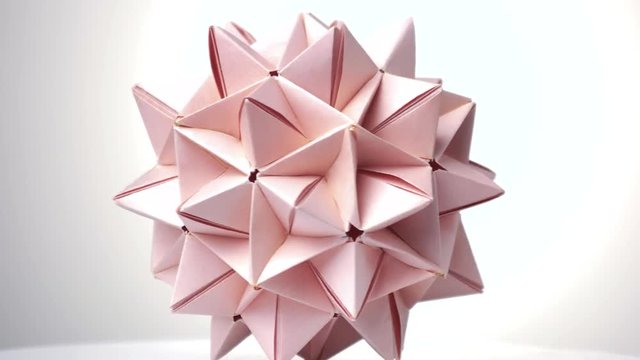 Close up origami spiky ball. Bright isolated background.