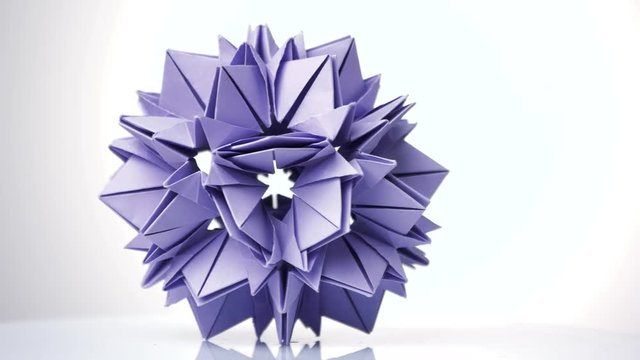 Purple origami transforming spiky ball. Bright isolated background.