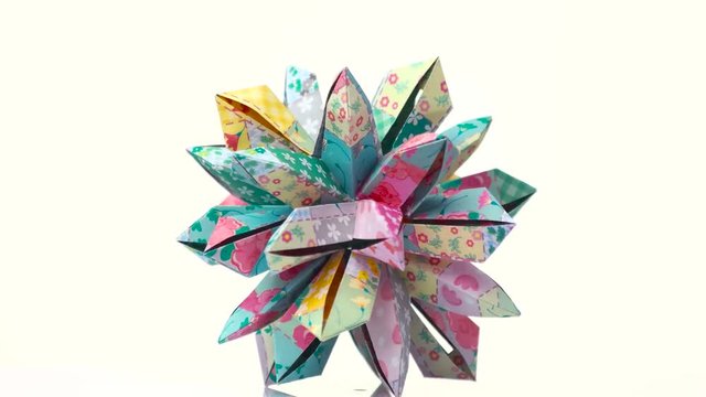 Colourful decorated origami transforming spiky ball. Bright isolated background.