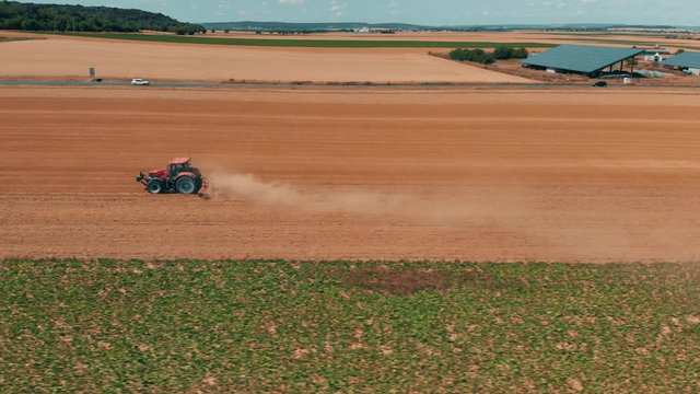 Aerial drone view of red tracor working in wheat field. Agriculture and environment in European Union.
