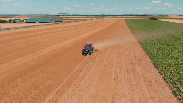 Aerial drone view of red tracor working in wheat field. Agriculture and environment in European Union.