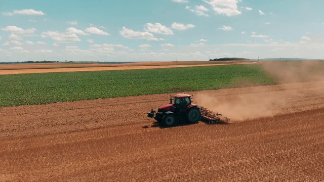 Aerial drone view of red tracor working in wheat field. Agriculture and environment in European Union.