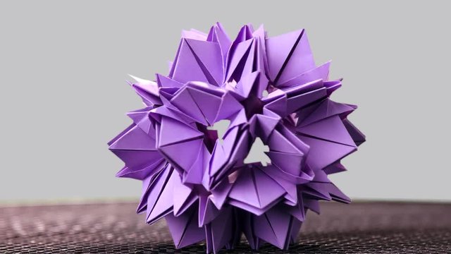 Purple origami sharp ball exposition. Rotation. Grey background.