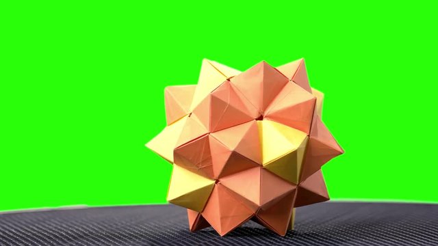 Orange origami spiky ball exposition. Green hromakey background for keying.
