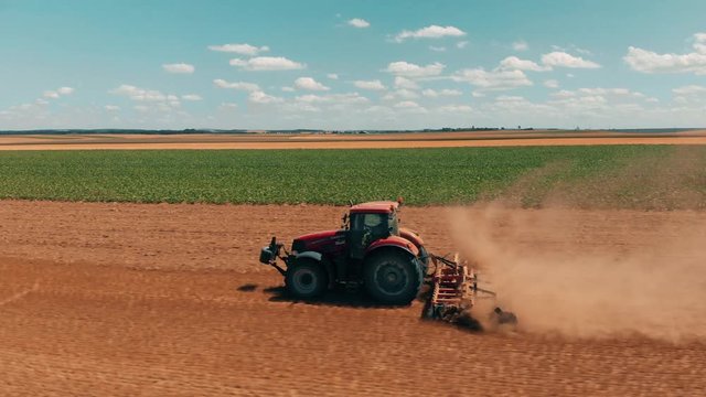 Aerial drone view of red tracor working in wheat field. Agriculture and environment in European Union.
