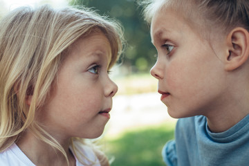 Profile of small girls standing and looking at each other with eyes wide open. They are playing games outside with joy