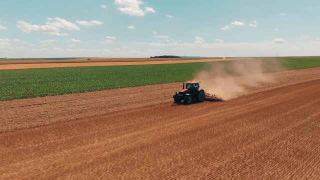Aerial drone view of red tracor working in wheat field. Agriculture and environment in European Union.
