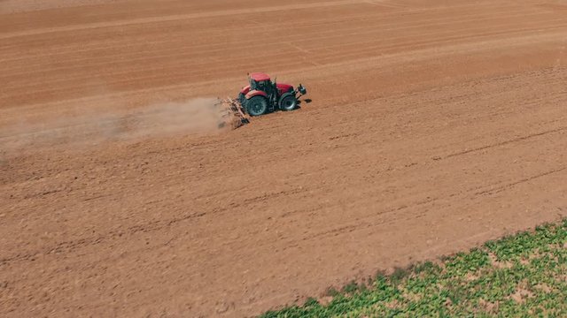 Aerial drone view of red tracor working in wheat field. Agriculture and environment in European Union.