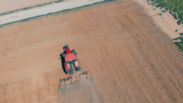 Aerial drone view of red tracor working in wheat field. Agriculture and environment in European Union.