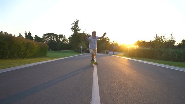 The elderly man rollerblading on the alley on a sunrise background. slow motion
