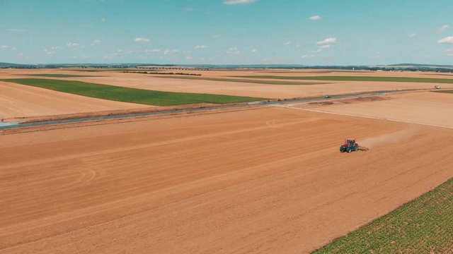 Aerial drone view of red tracor working in wheat field. Agriculture and environment in European Union.