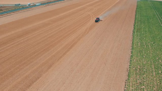 Aerial drone view of red tracor working in wheat field. Agriculture and environment in European Union.