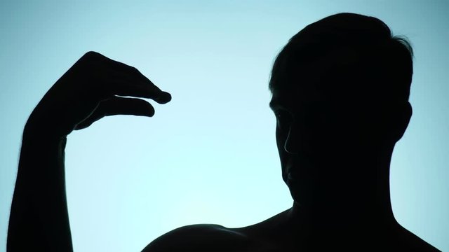 silhouette of a man on a blue background. the funny man plays the shadow theater. 4k, slow motion