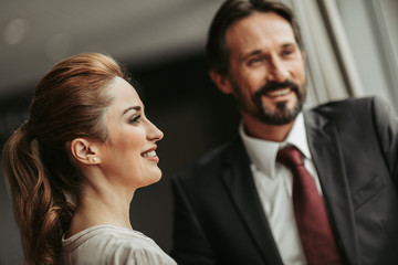 Side view beaming lady talking with glad unshaven man during rest at job. Pleased partners during communication concept