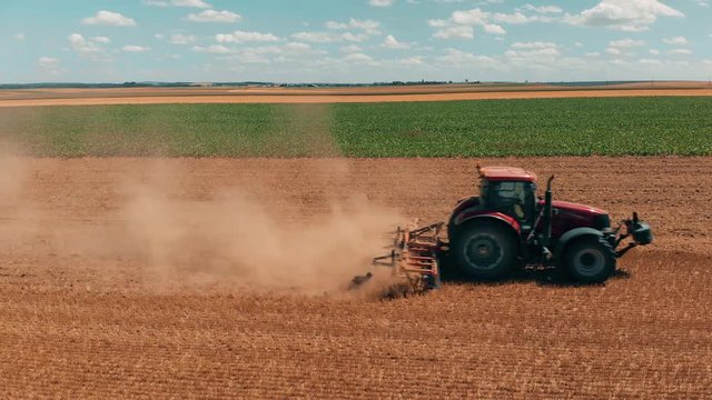 Aerial drone view of red tracor working in wheat field. Agriculture and environment in European Union.