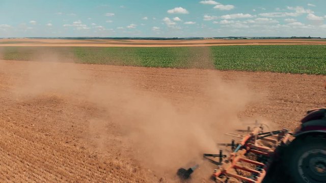 Aerial drone view of red tracor working in wheat field. Agriculture and environment in European Union.