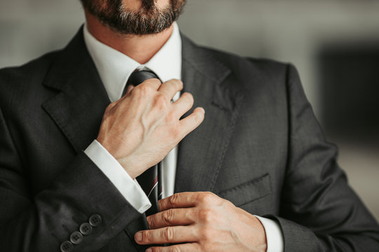 Close up businessman hands adjusting tie. He wearing modern suit. Modern clothes of entrepreneur concept