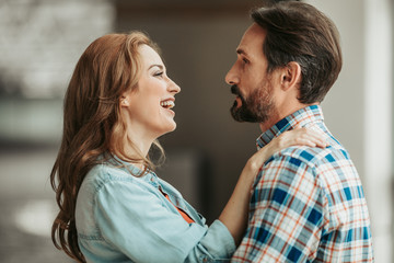 Side view cheerful wife embracing outgoing unshaven husband. They talking together