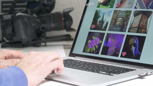 A cameraman Watching images files photo pictures wall in notebook or social network. Documentary camera in background