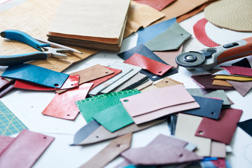 Close-up of workplace with samples of leather fabric and worktools in workshop